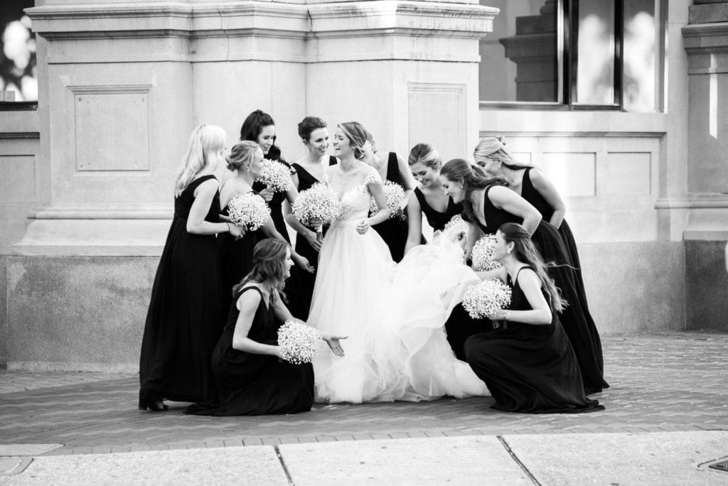 bride and her bridesmaids in a black and white photo, holding bouquets and laughing