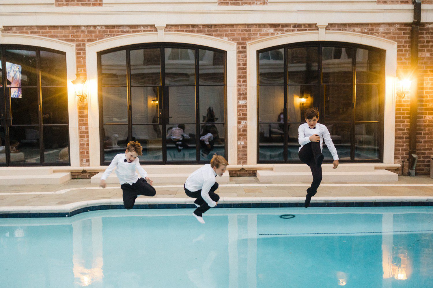 Boys jumping into pool at wedding