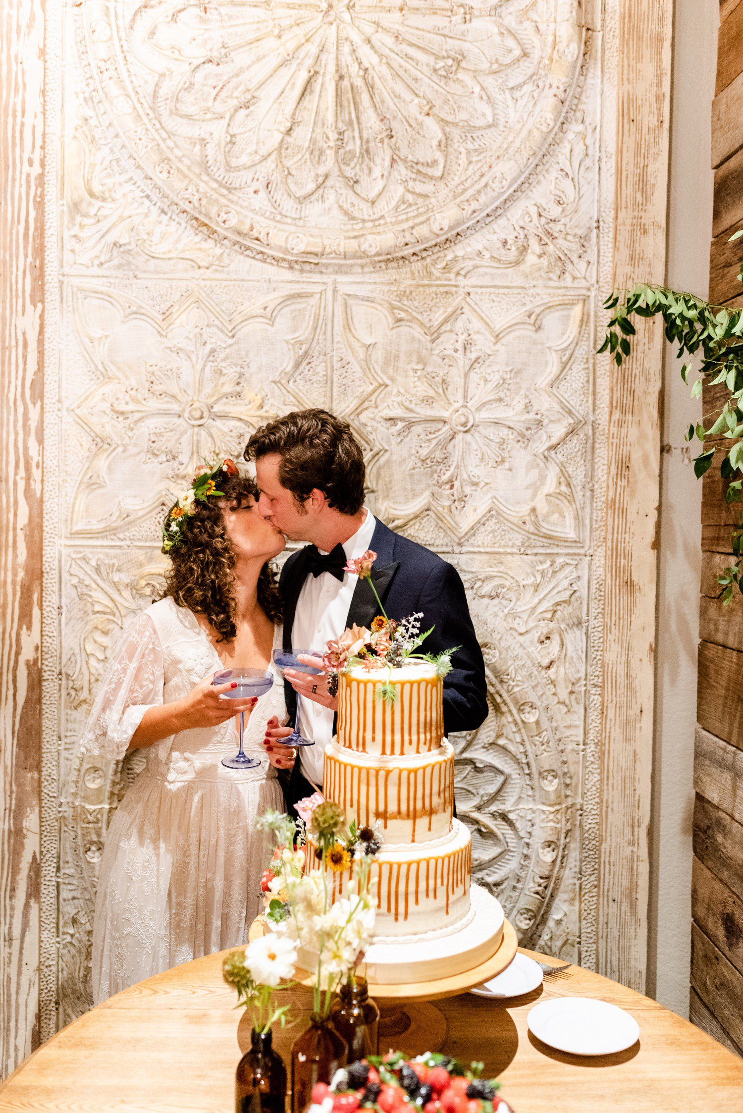 Bride and groom kiss with wedding cake