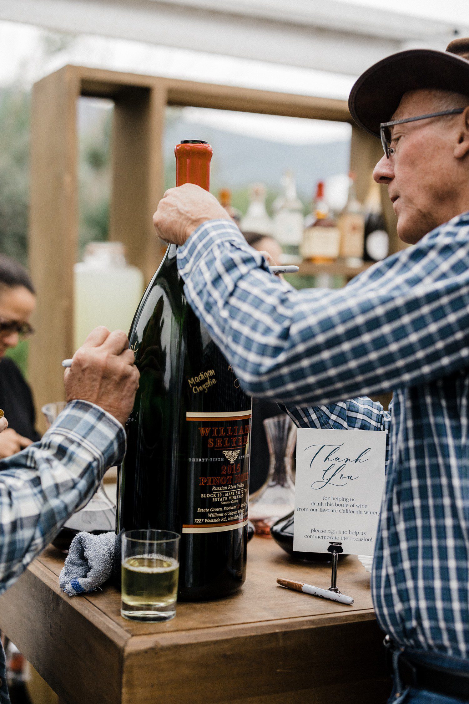 Wedding guests signing giant wine bottle. 