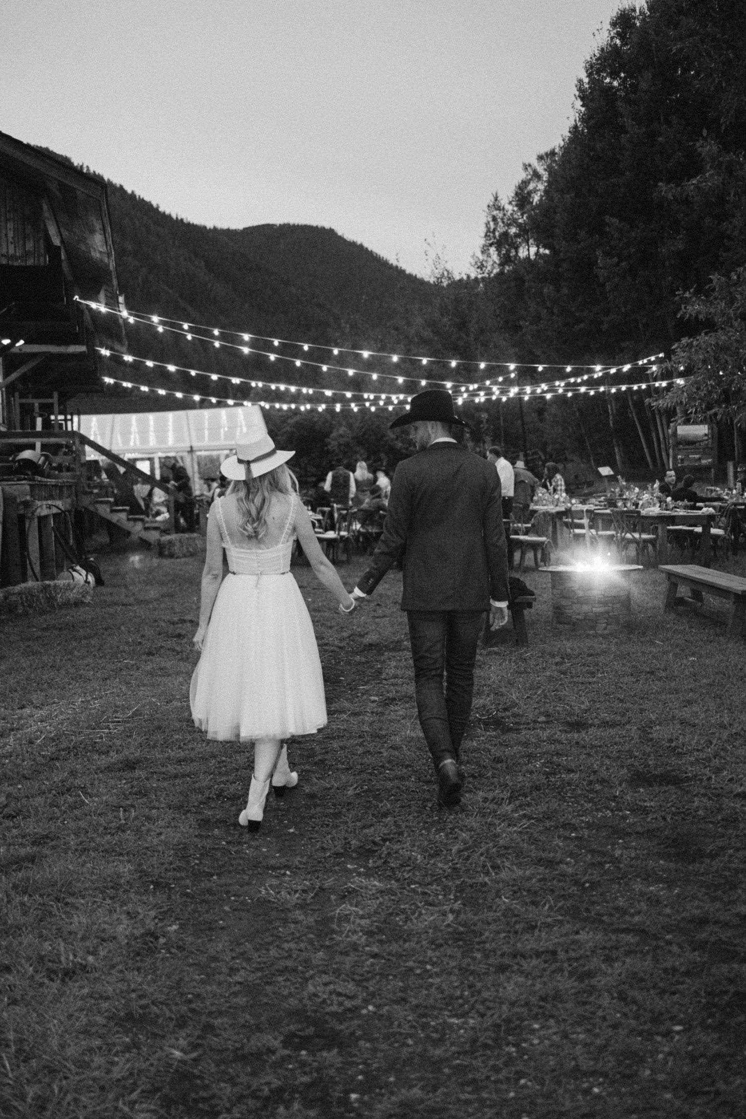 Bride and groom holding hands and walking at rehearsal dinner. 