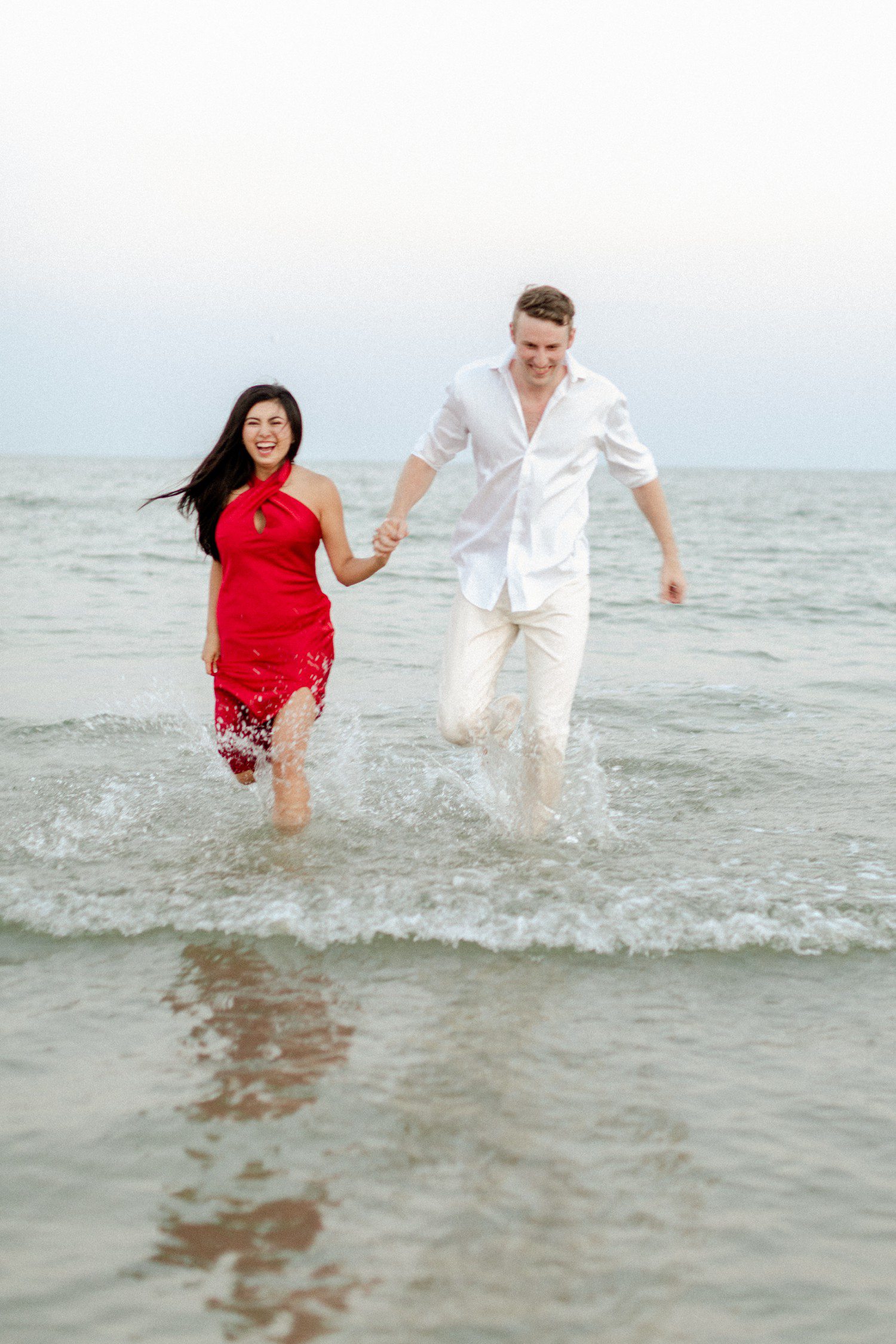Couple running on Galveston beach for engagement photos. 