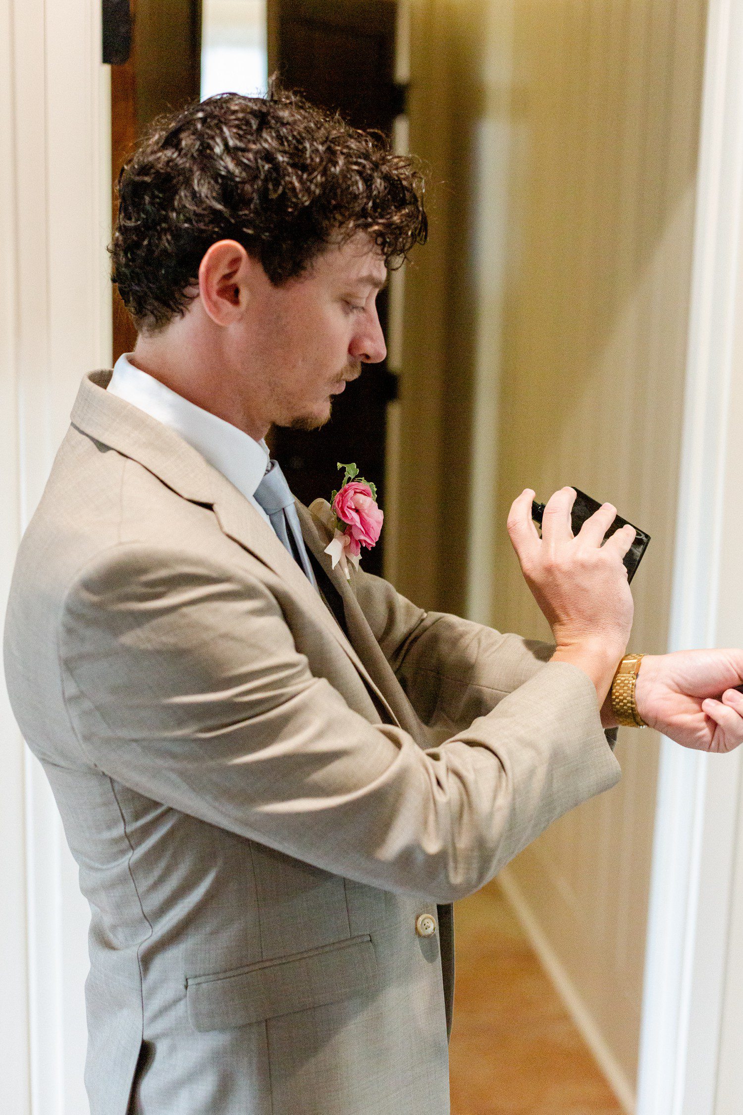Groom putting on cologne for wedding day.