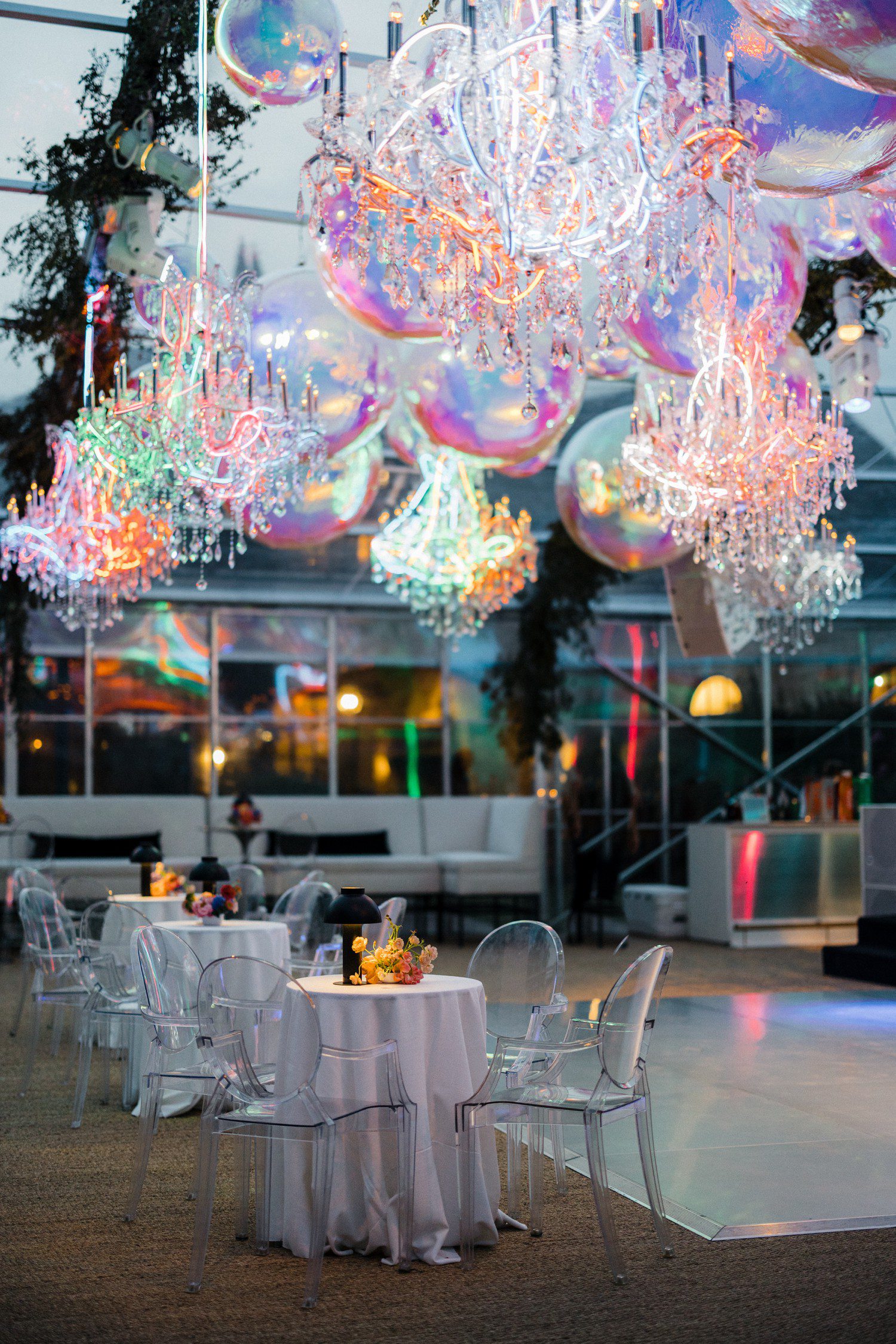 Wedding dance floor ceiling with chandeliers wrapped in neon lights and balloons.
