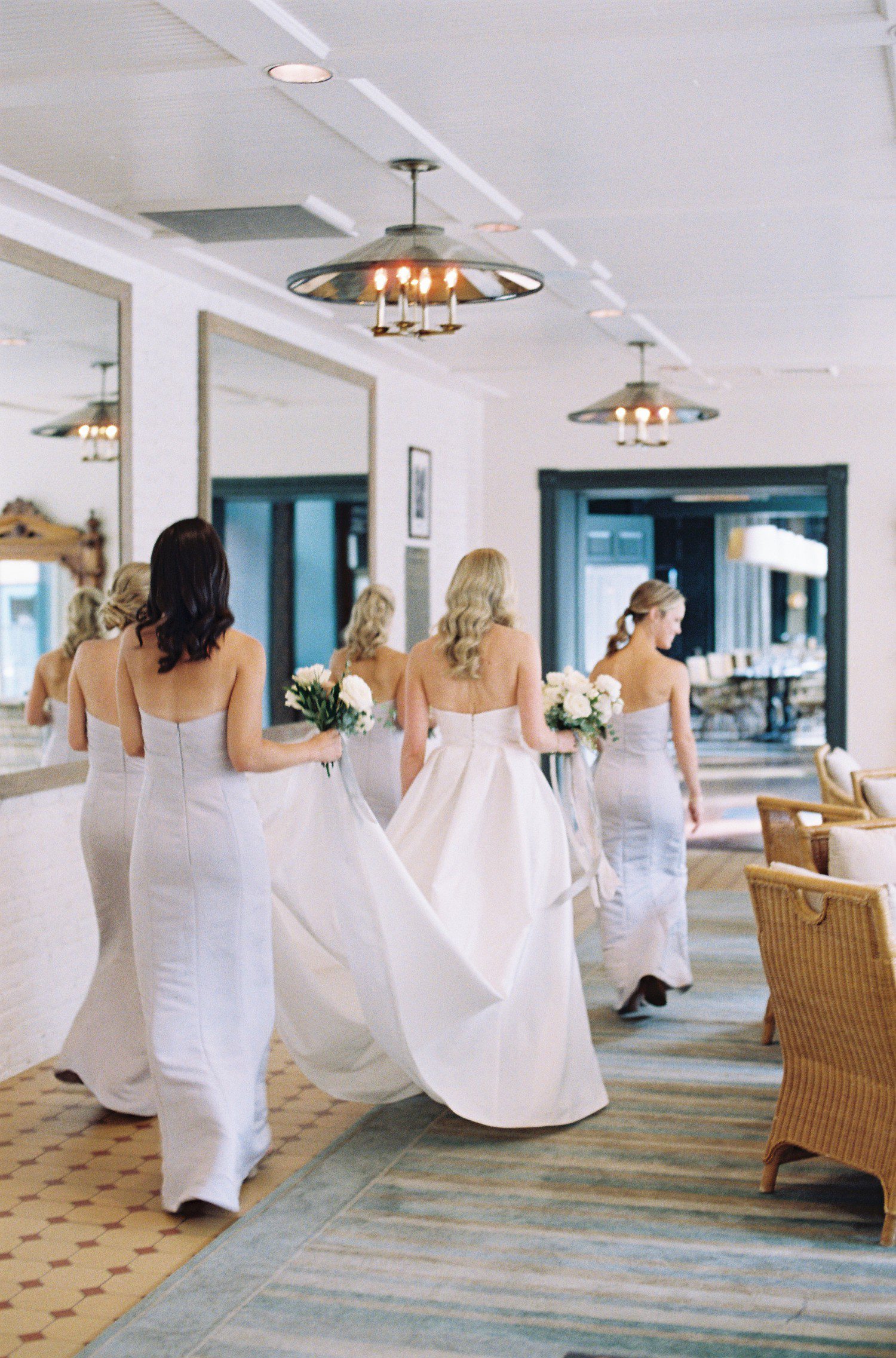Bride and bridesmaids walking through Hotel Jerome. 