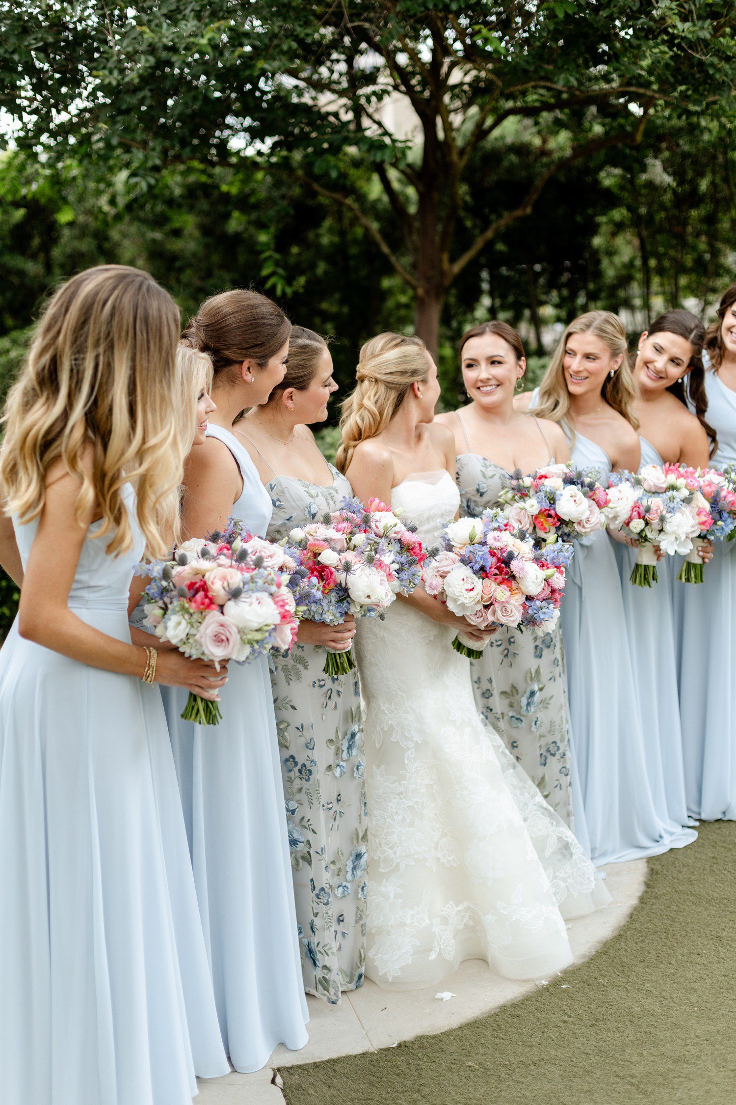 Bride and bridesmaids in light blue dresses holding colorful bouquets. 