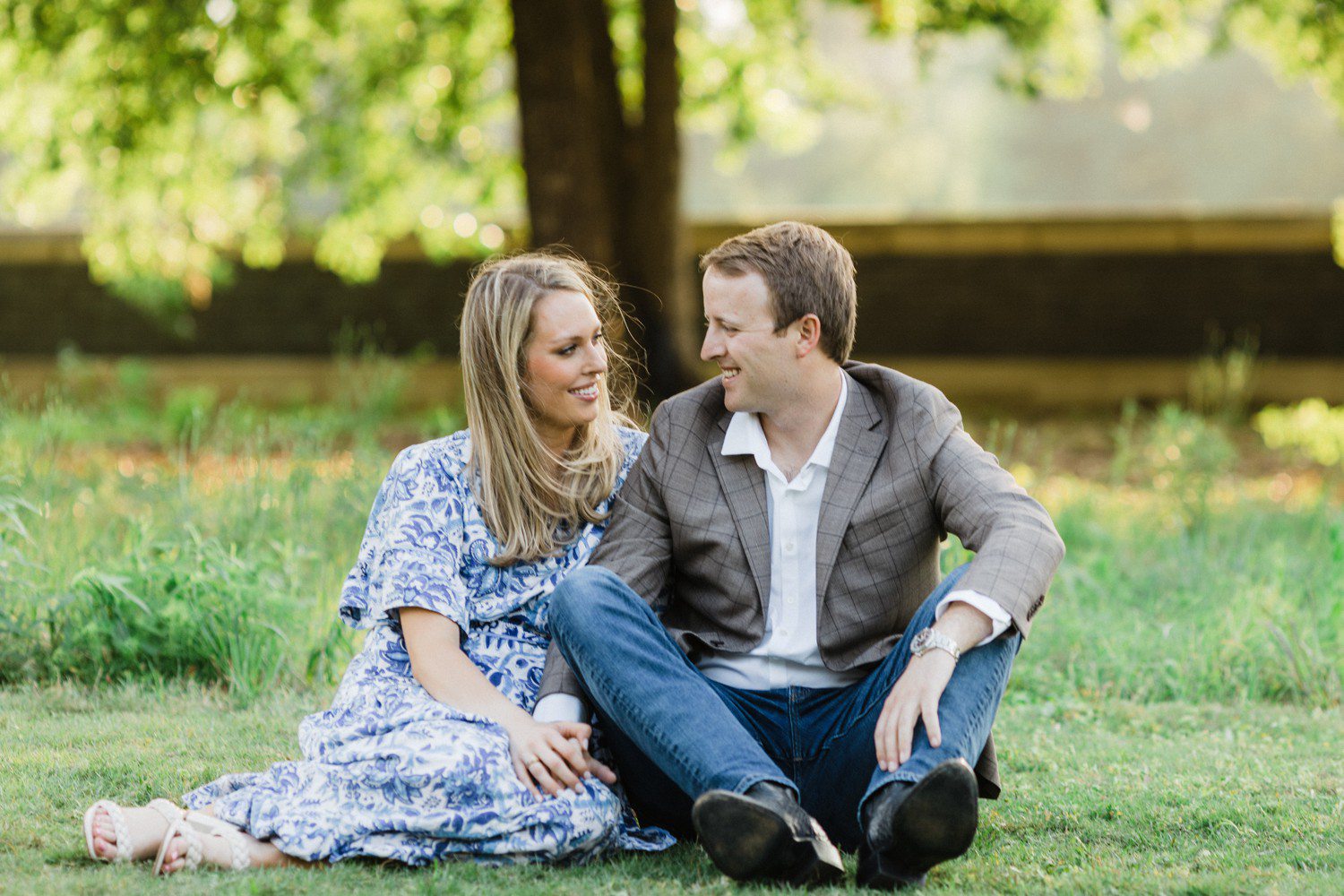 Couple sitting in grass for engagement session at Eastern Glades in Houston. 