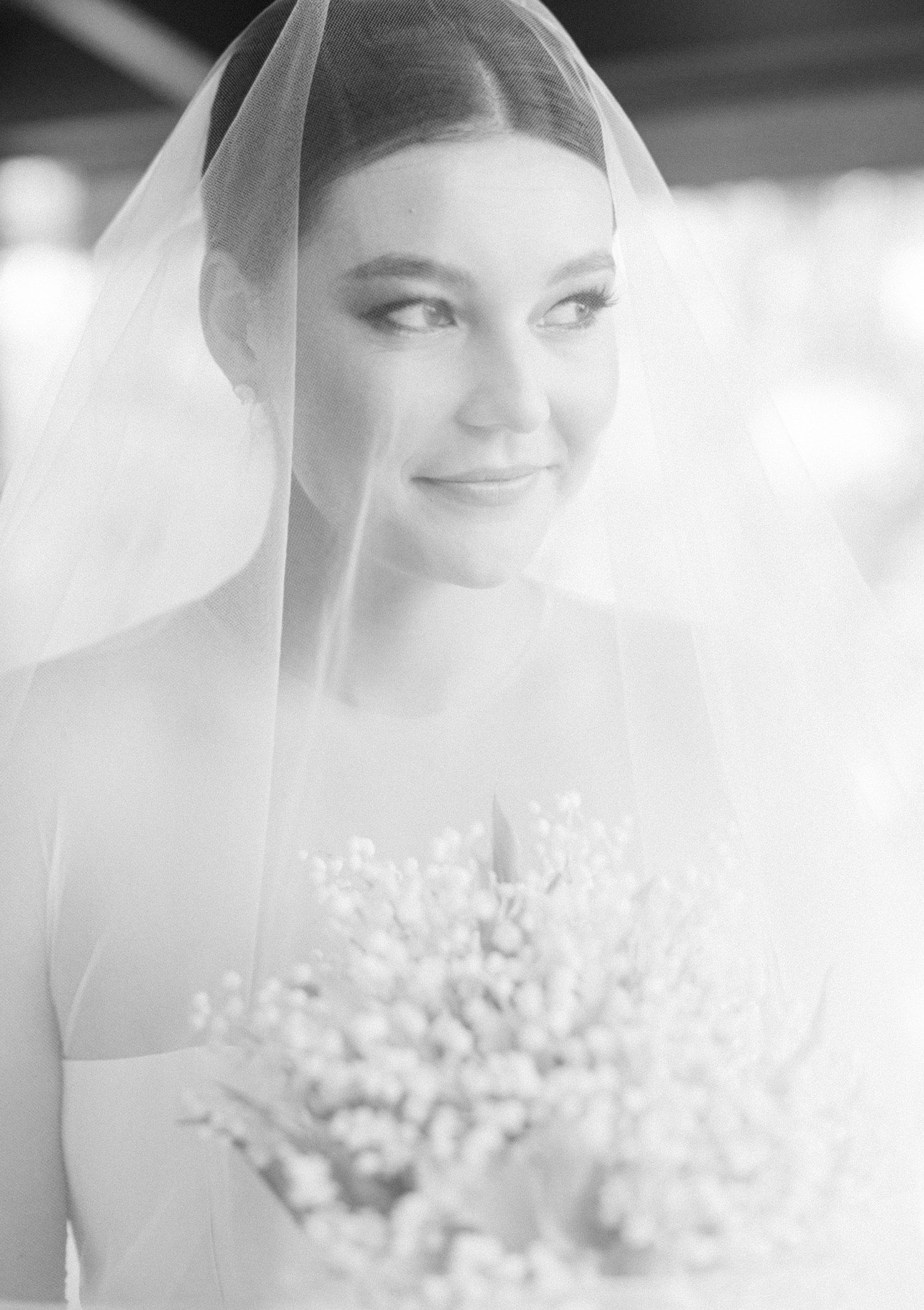 Bride holding bouquet and looking out from veil. 