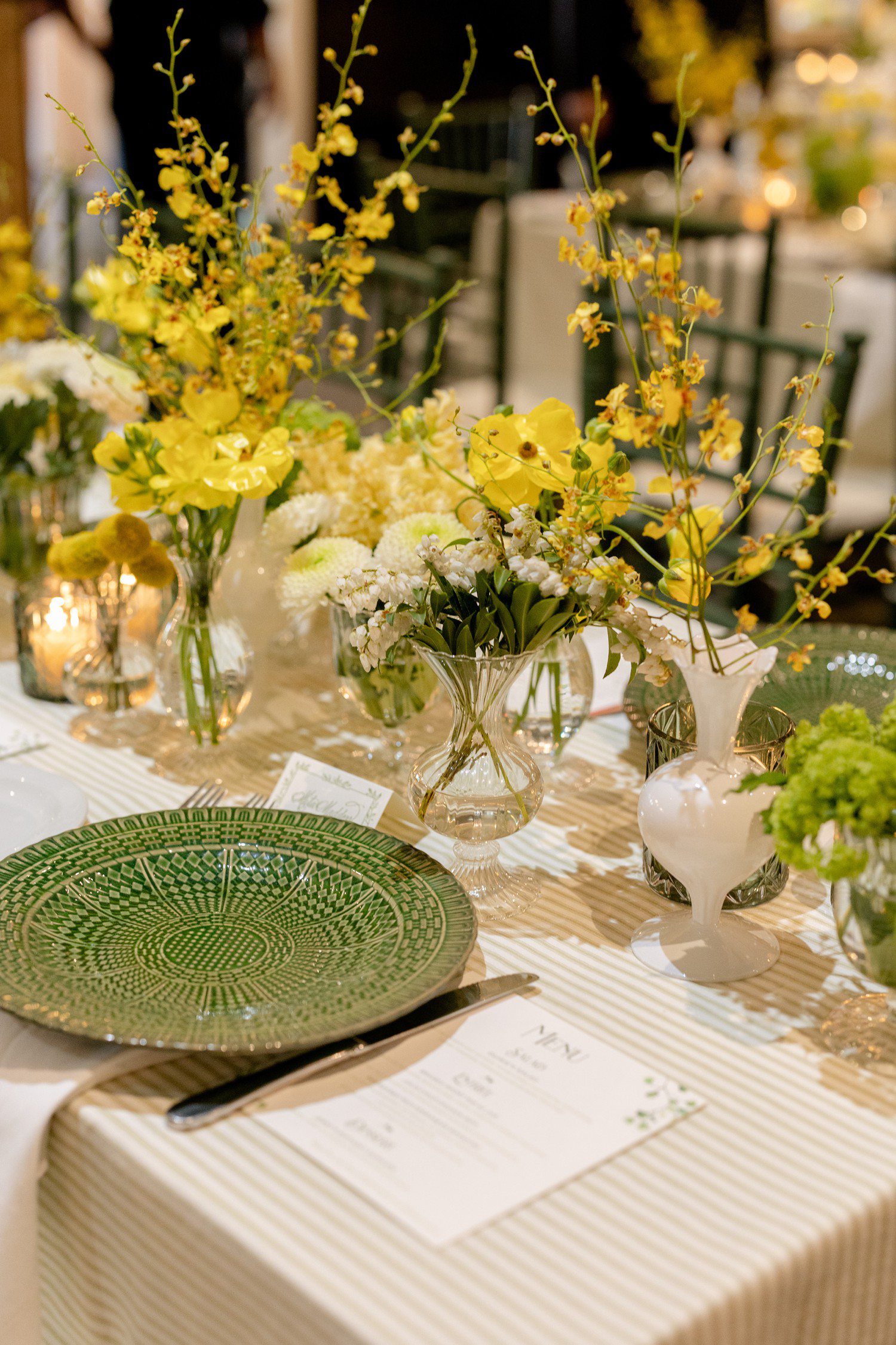 Yellow flowers and green flatware for wedding rehearsal table decor.