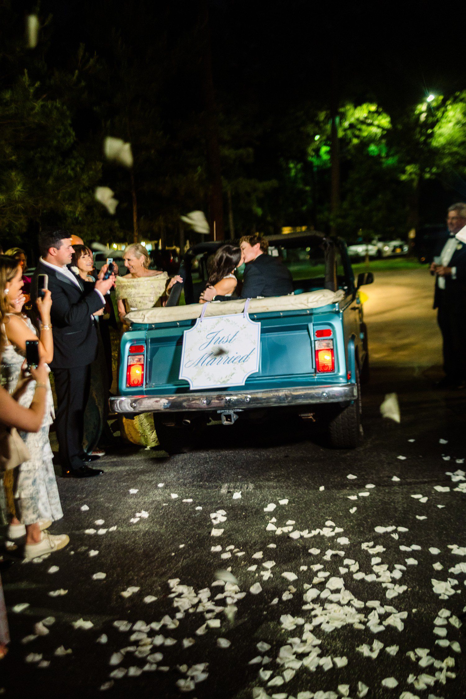 Bride and groom kissing in wedding getaway car.