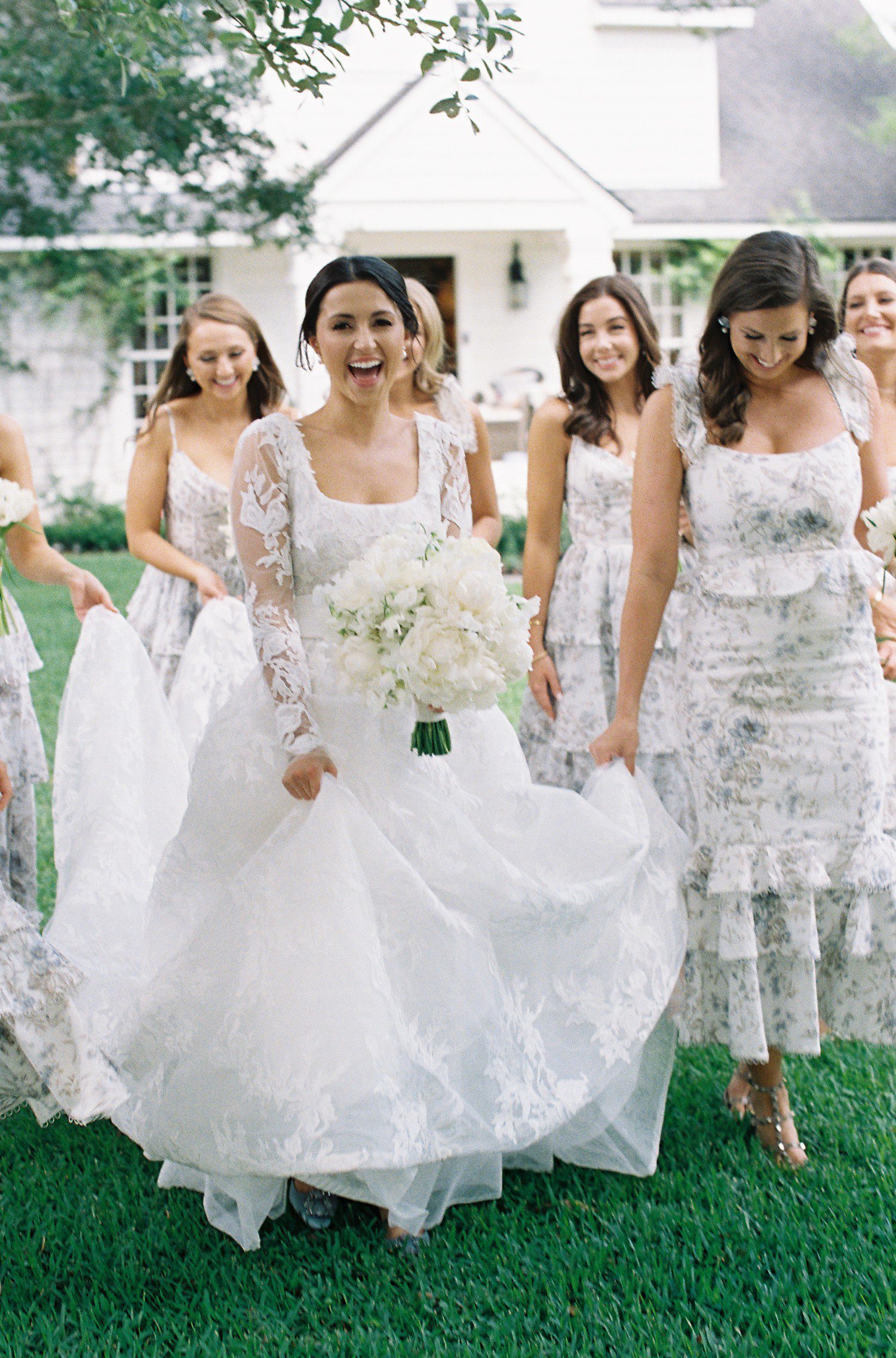 Bride walking with bridesmaids holding white bouquet.