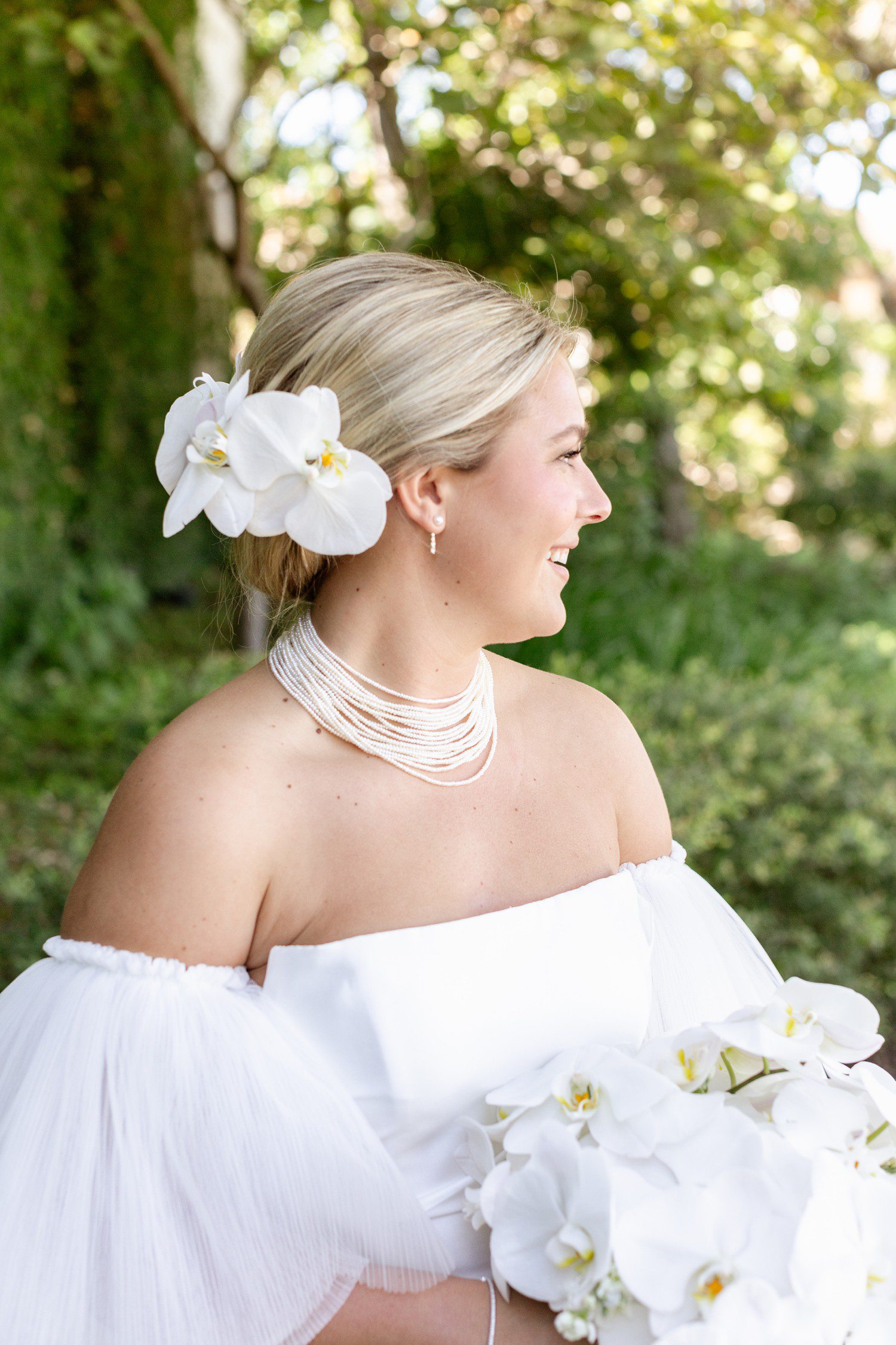 Bride with white orchids in hair and white orchid bouquet.
