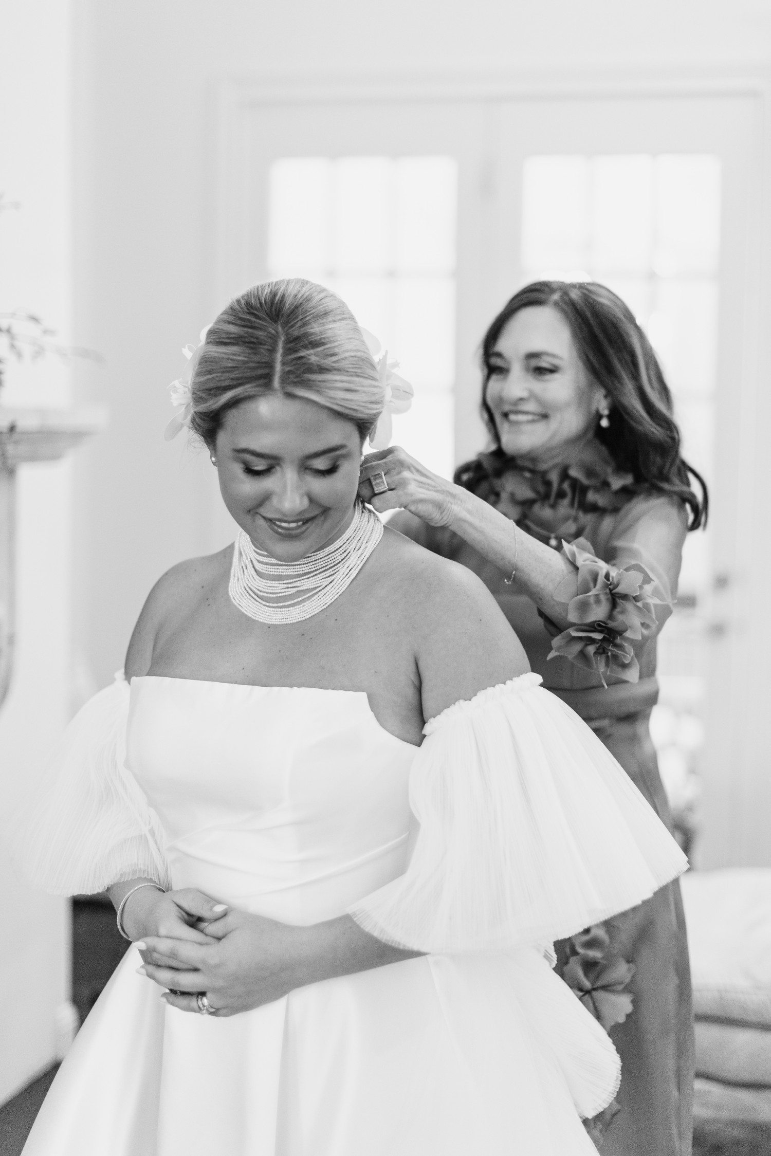 Bride smiling as wedding necklace is being put on.