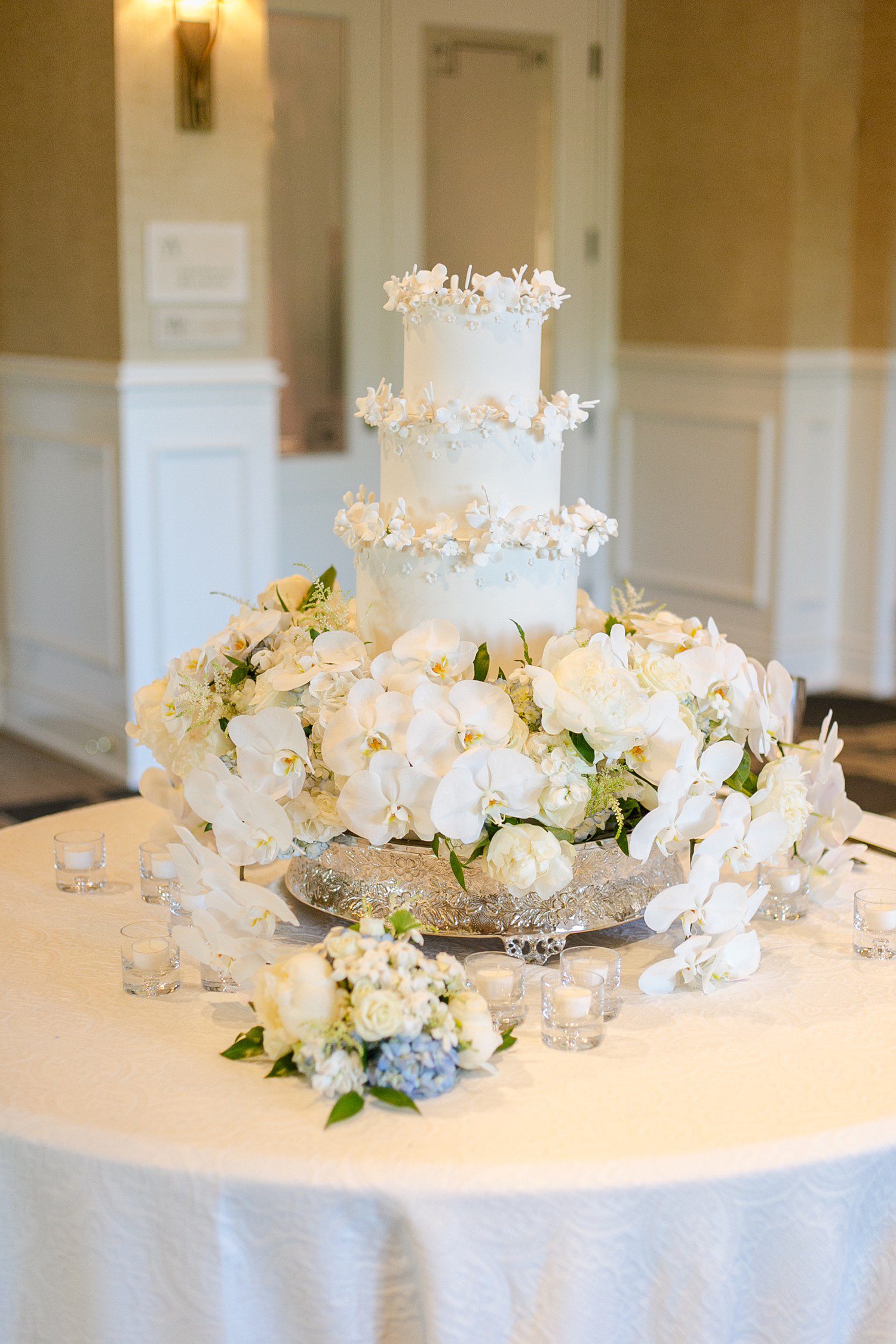 Tiered white wedding cake with white orchid flowers.
