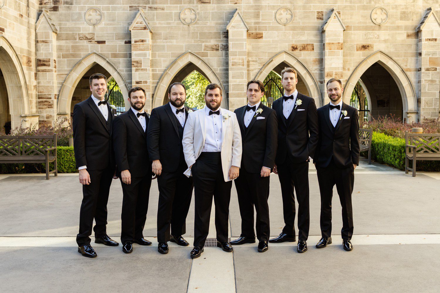 Groom in white suit jacket and groomsmen in all back.