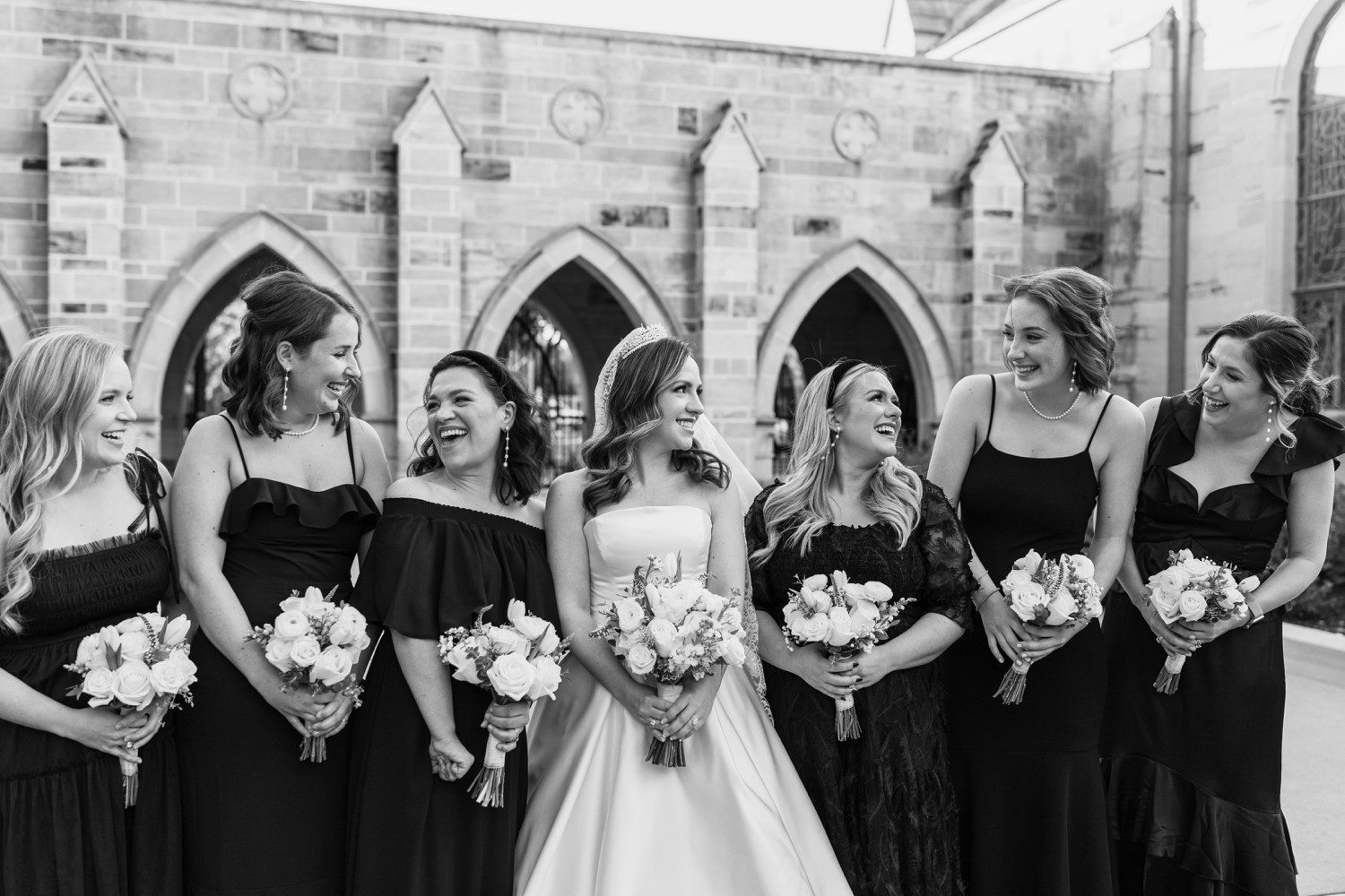 Bride and bridesmaids smiling at each other.
