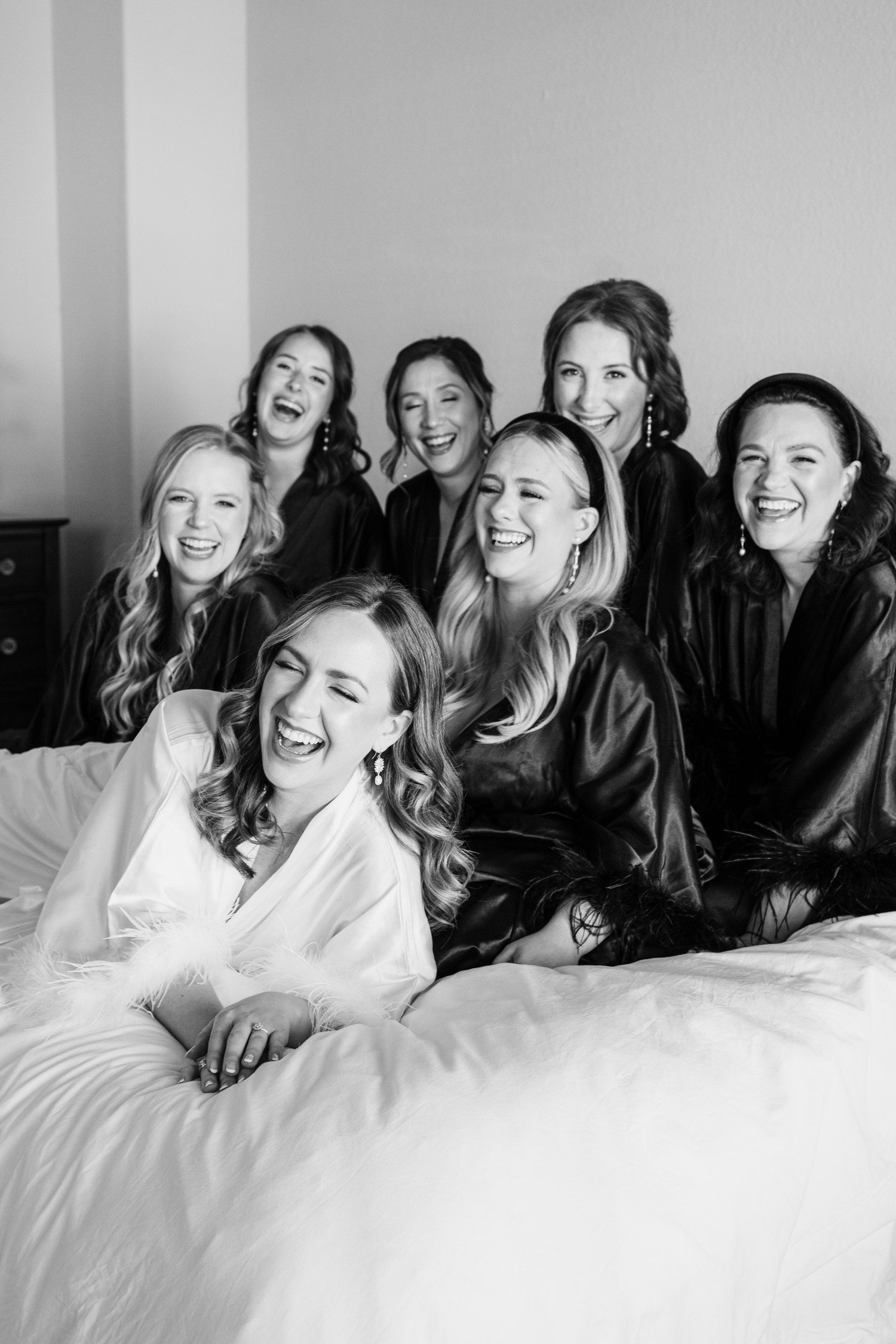 Bride and bridesmaids laughing during robe photos.