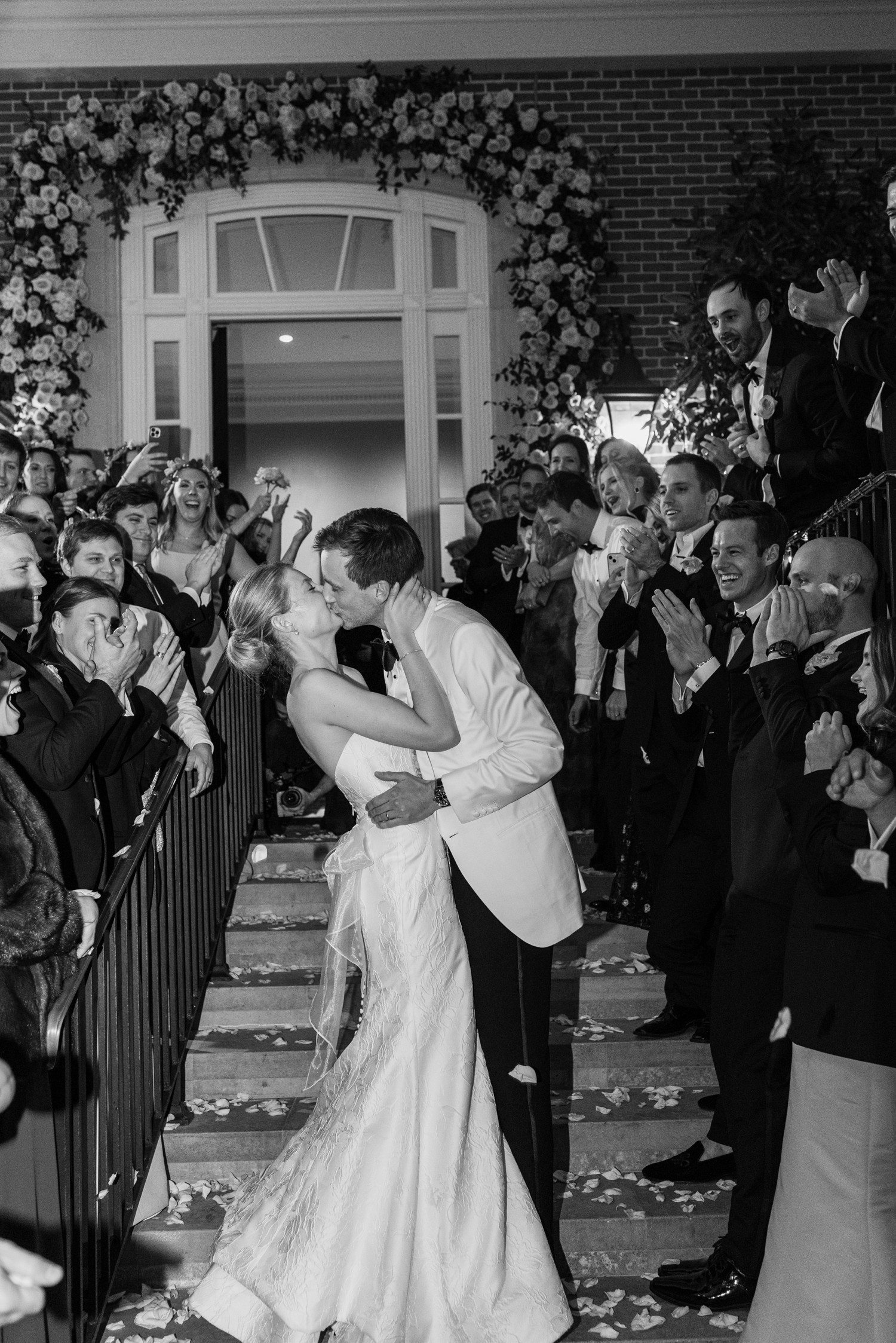 Bride and groom kissing during grand exit for their wedding at the Houston Country Club. 