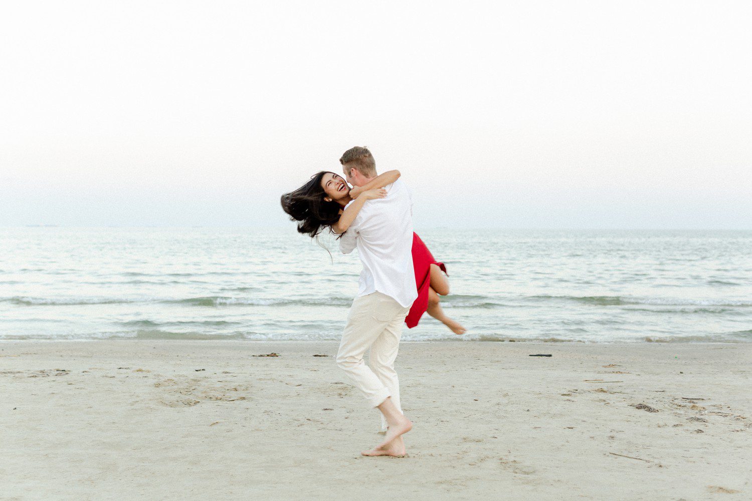 Galveston beach engagement photos with guy picking up girl.