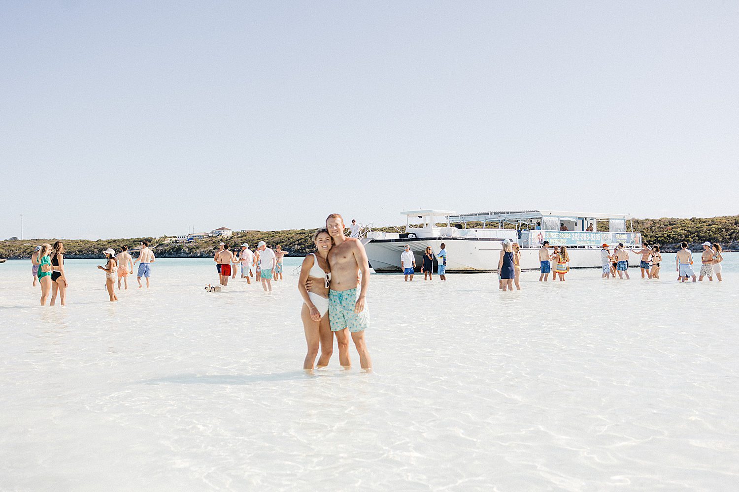 Couple in clear water in front of chartered boat in the Bahamas