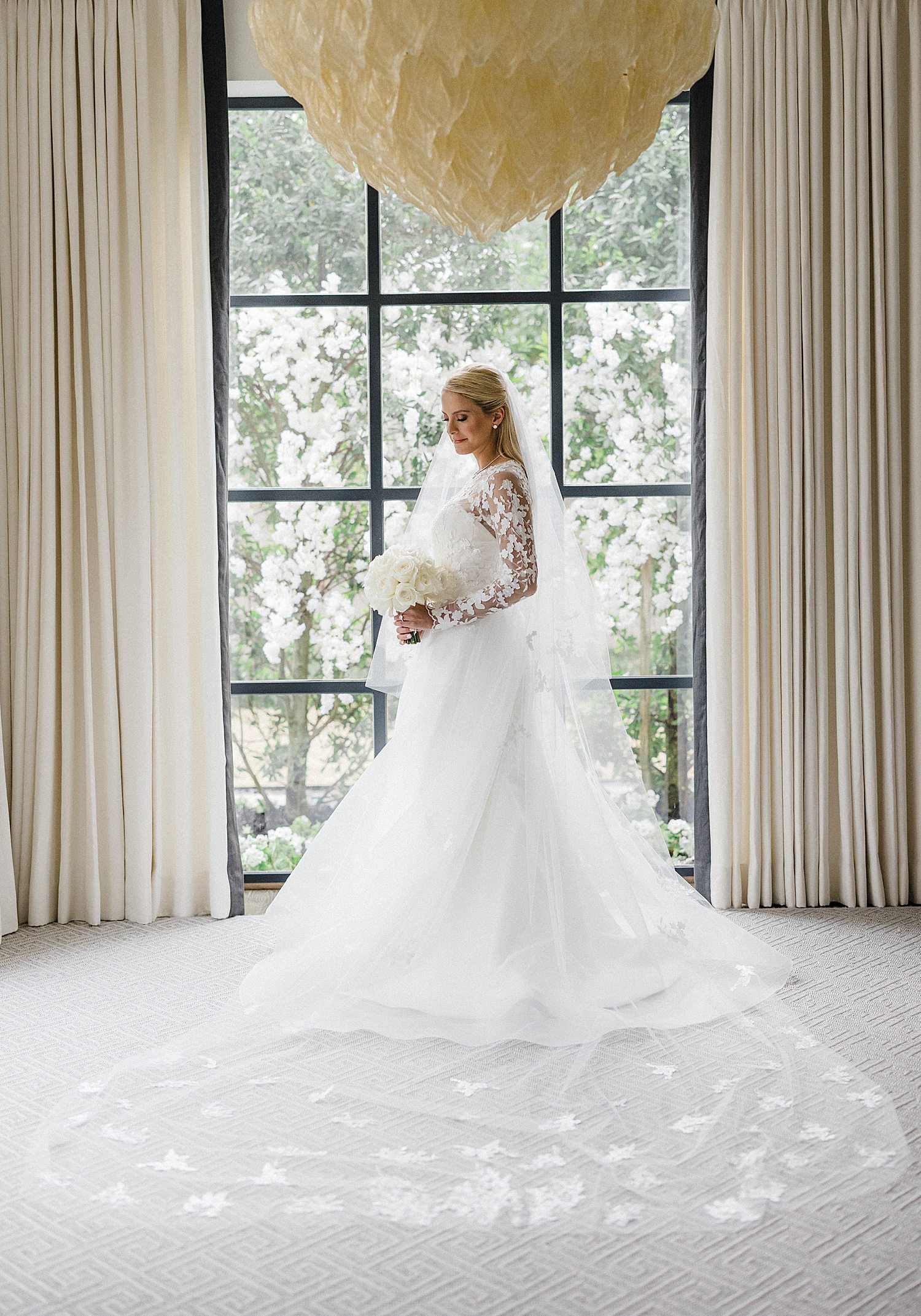 Bride holding bouquet in front of window