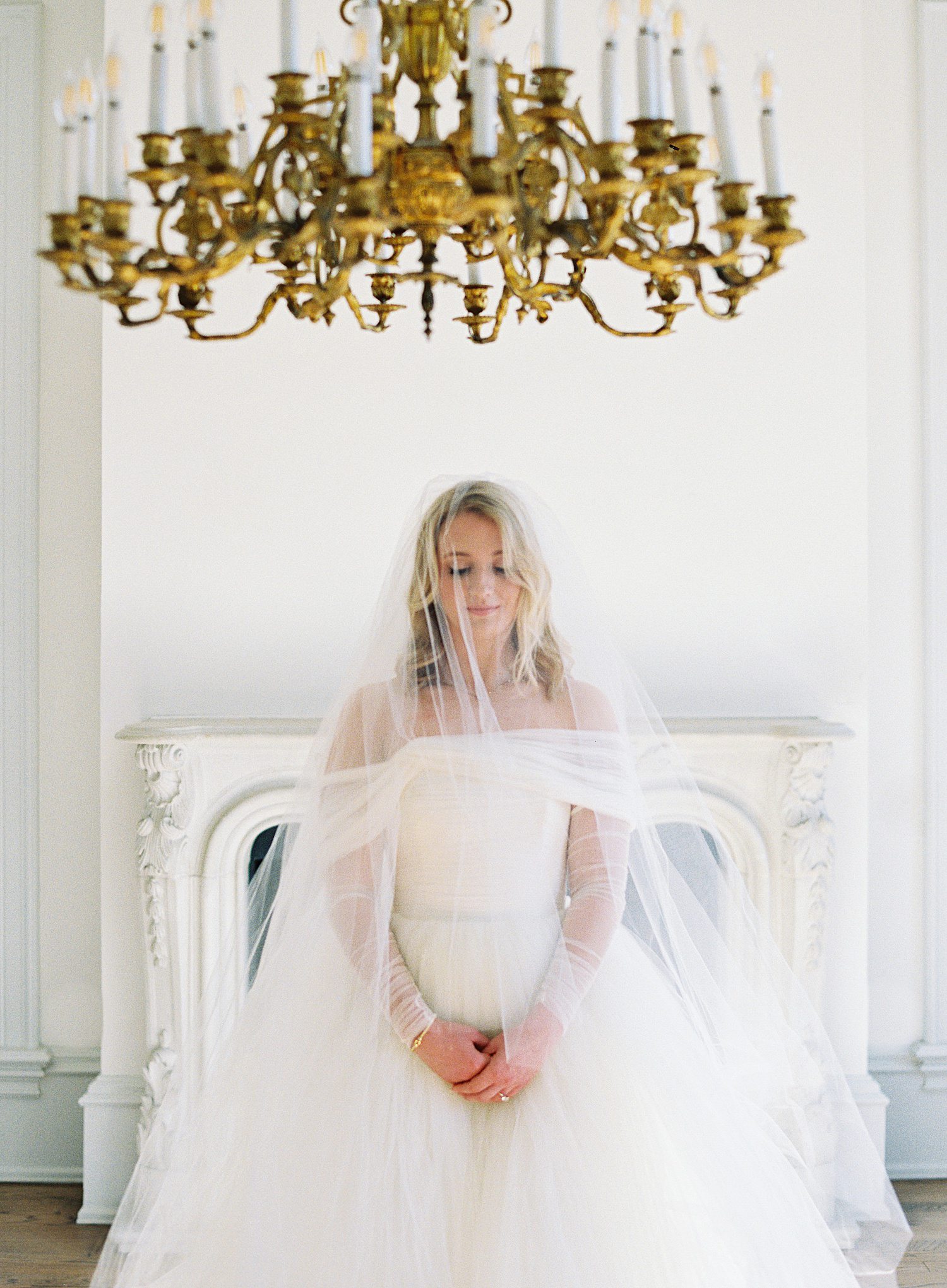 Bride standing under large chandelier at Creative Chateau in Houston