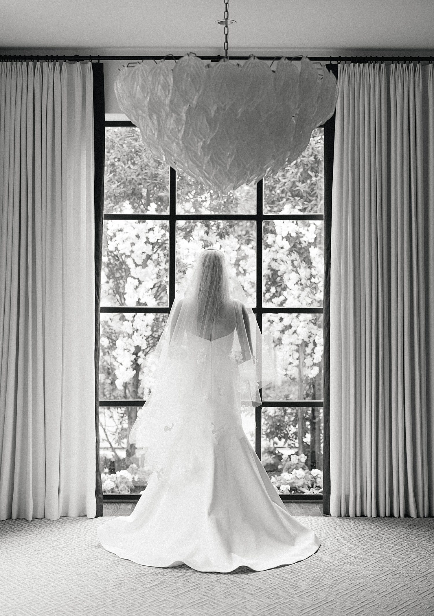 Black & white photo of bride in front of window