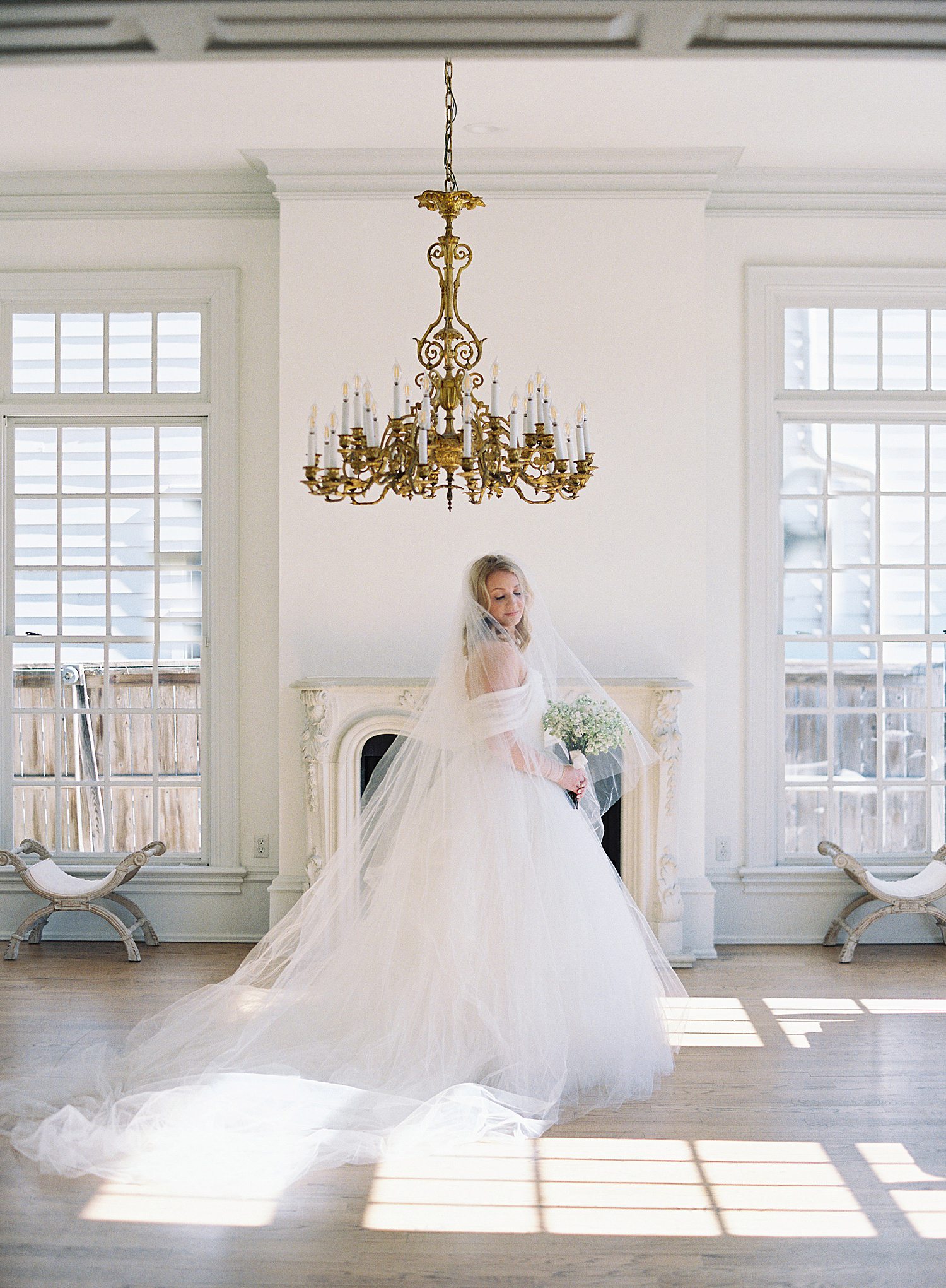 Bride standing under large chandelier at Creative Chateau in Houston