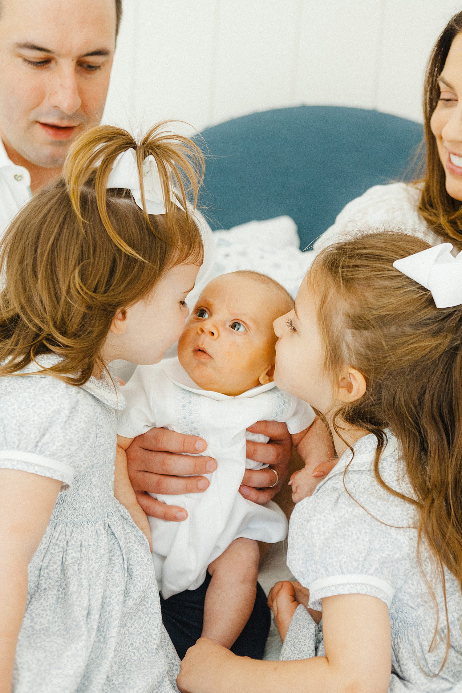 Sisters kissing baby brother