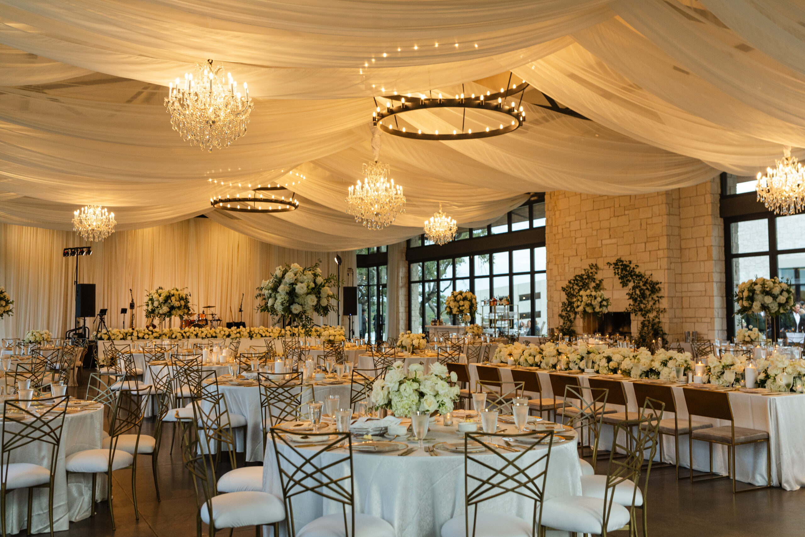 Tented ballroom wedding reception with white flowers and candles on tables