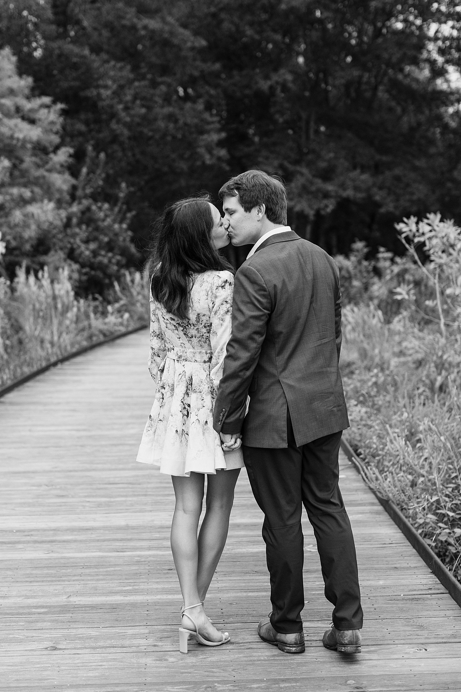 Engaged couple kissing on wooden footbridge