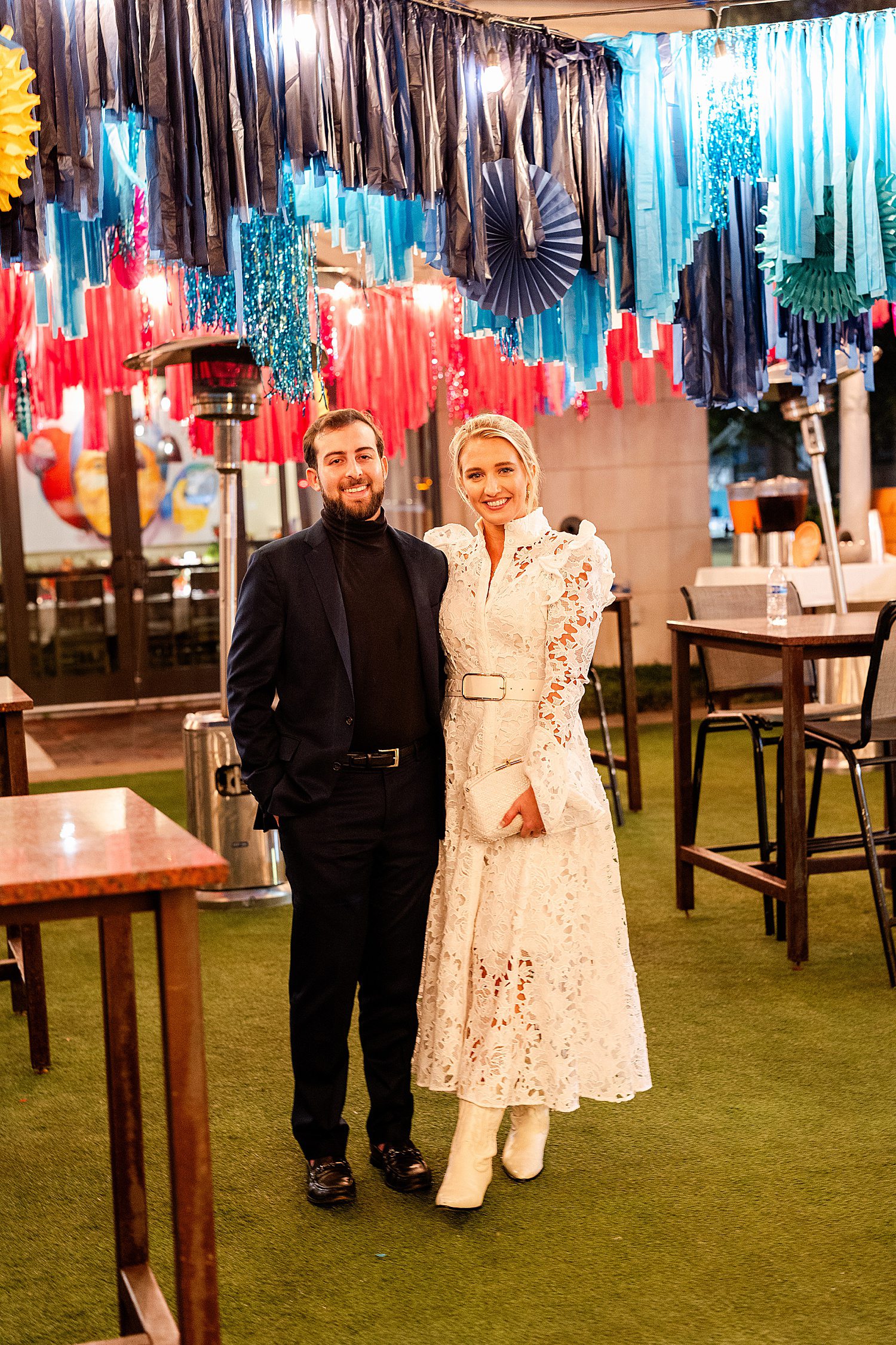 Engaged couple amid colorful streamers at their Houston rehearsal dinner