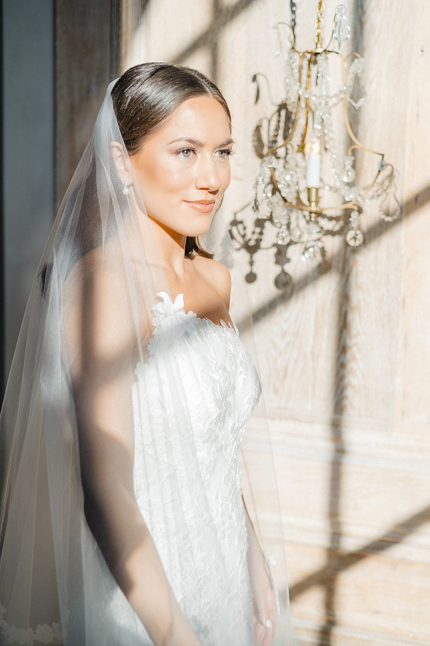 Bride in gown with asymmetrical neckline staring into the distance