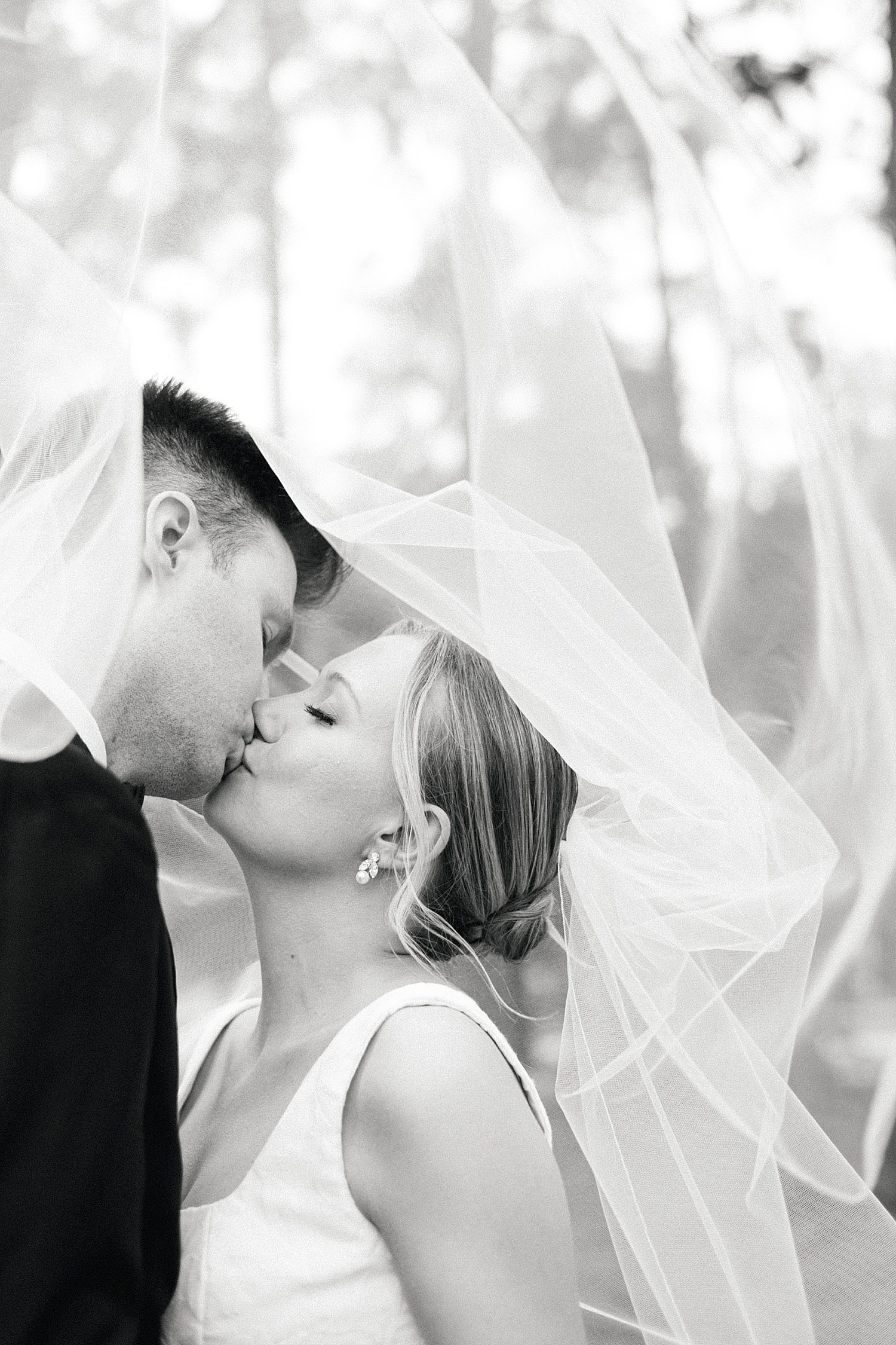 Bride and groom kissing under bride's veil