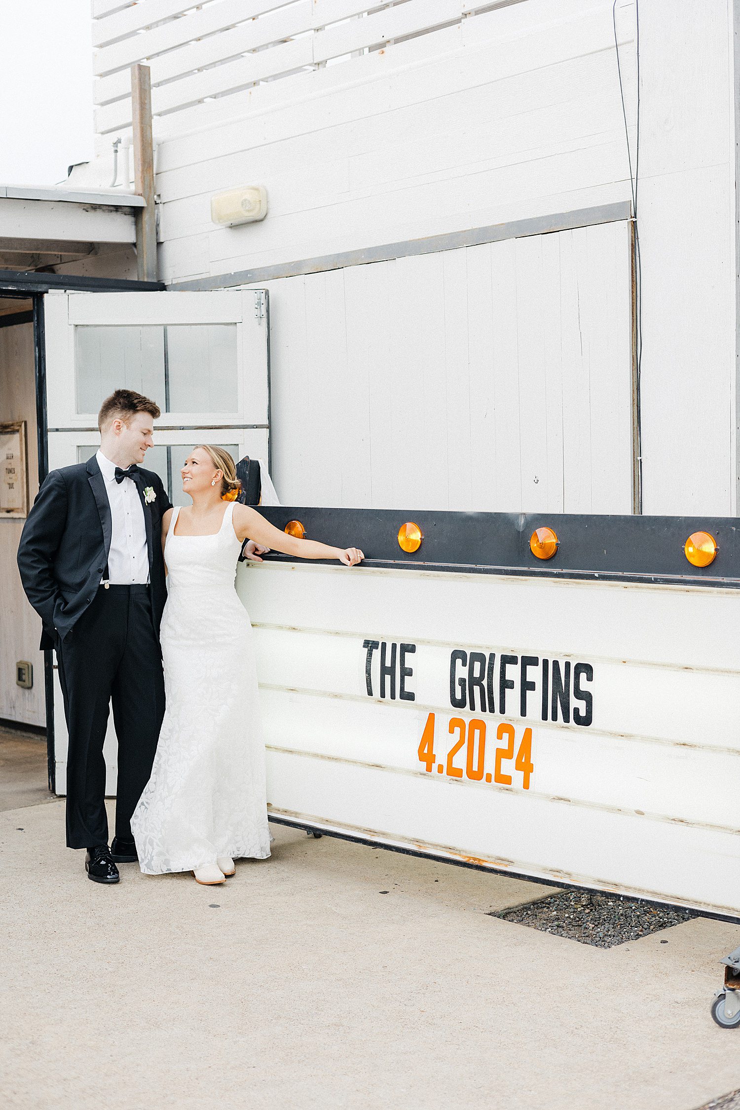 Newly married couple next to neon sign with their name on it