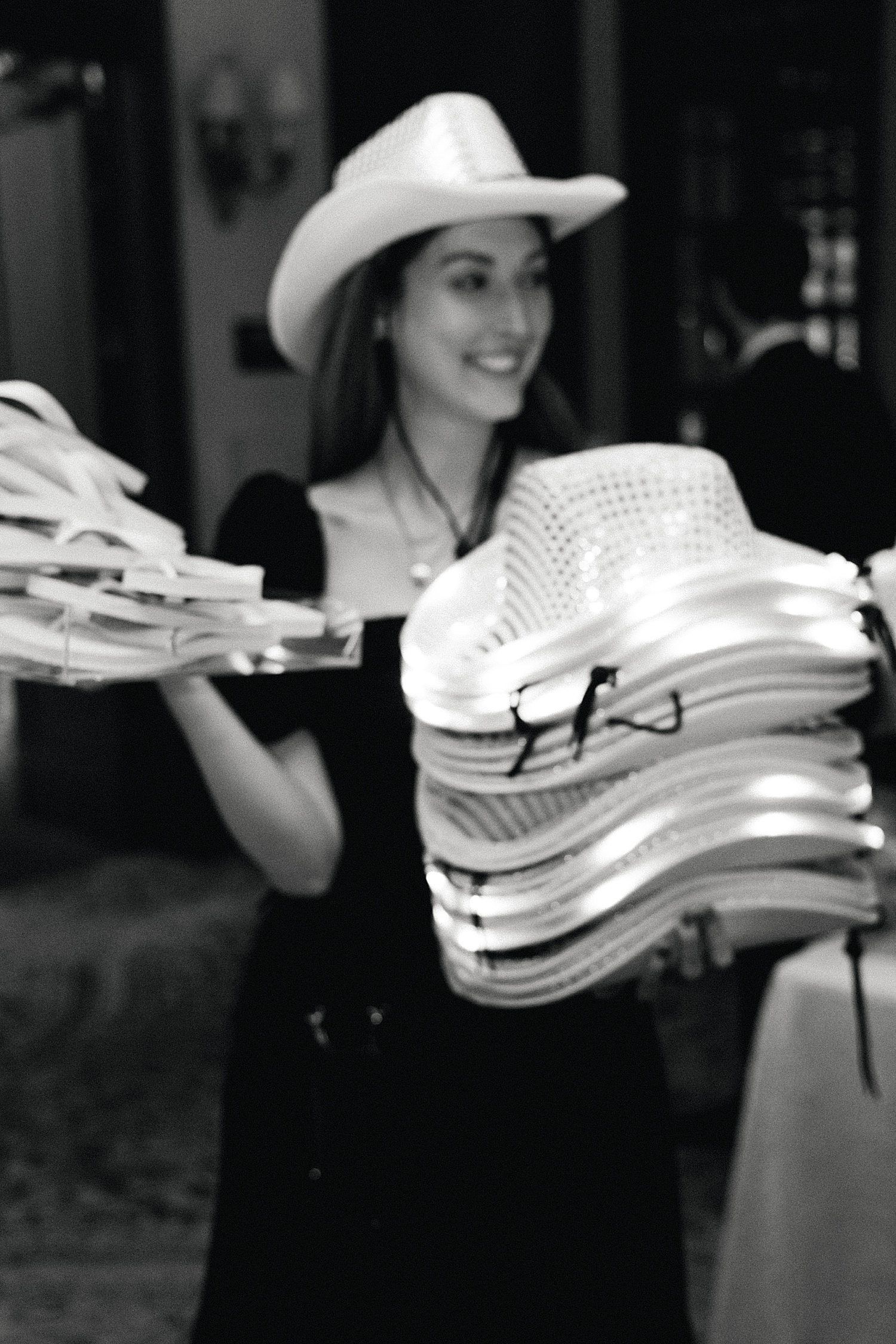 Wedding planner passing out light up cowboy hats at wedding reception at the Houstonian